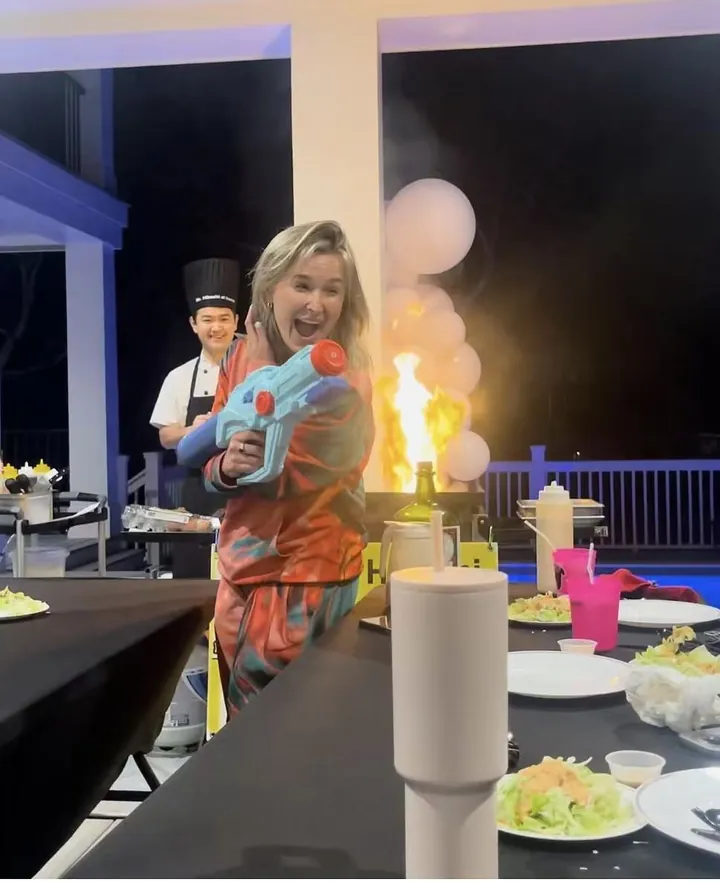 Guest enjoying a party game with a chef and hibachi flames in the background