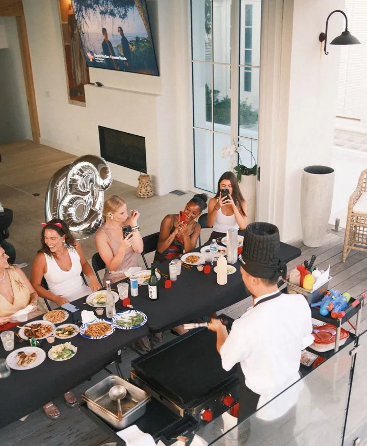 Hibachi chef at the grill with guests gathered around a table at home